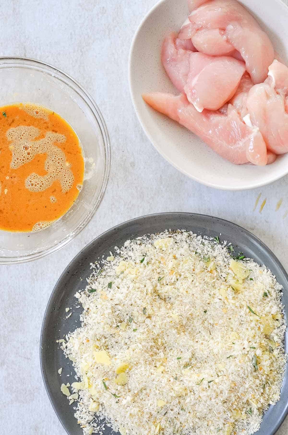 breadcrumbs on a plate next to chicken fingers