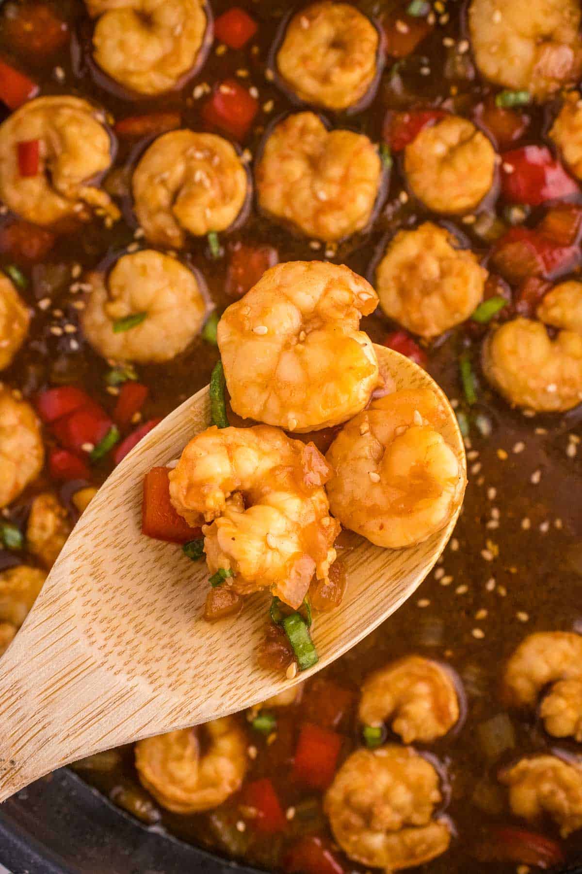 cooked mongolian shrimp on a wooden spoon
