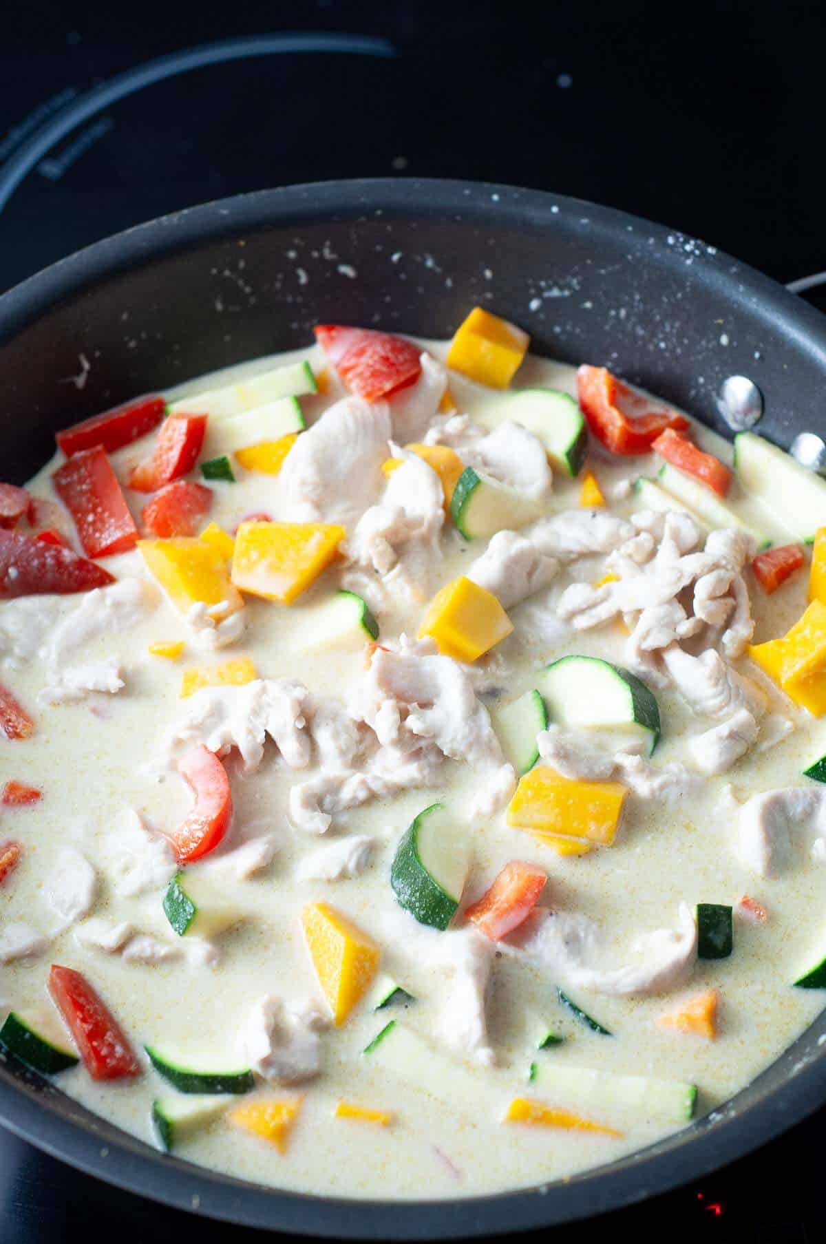 healthy thai green curry with chicken cooking in a pot on the stove