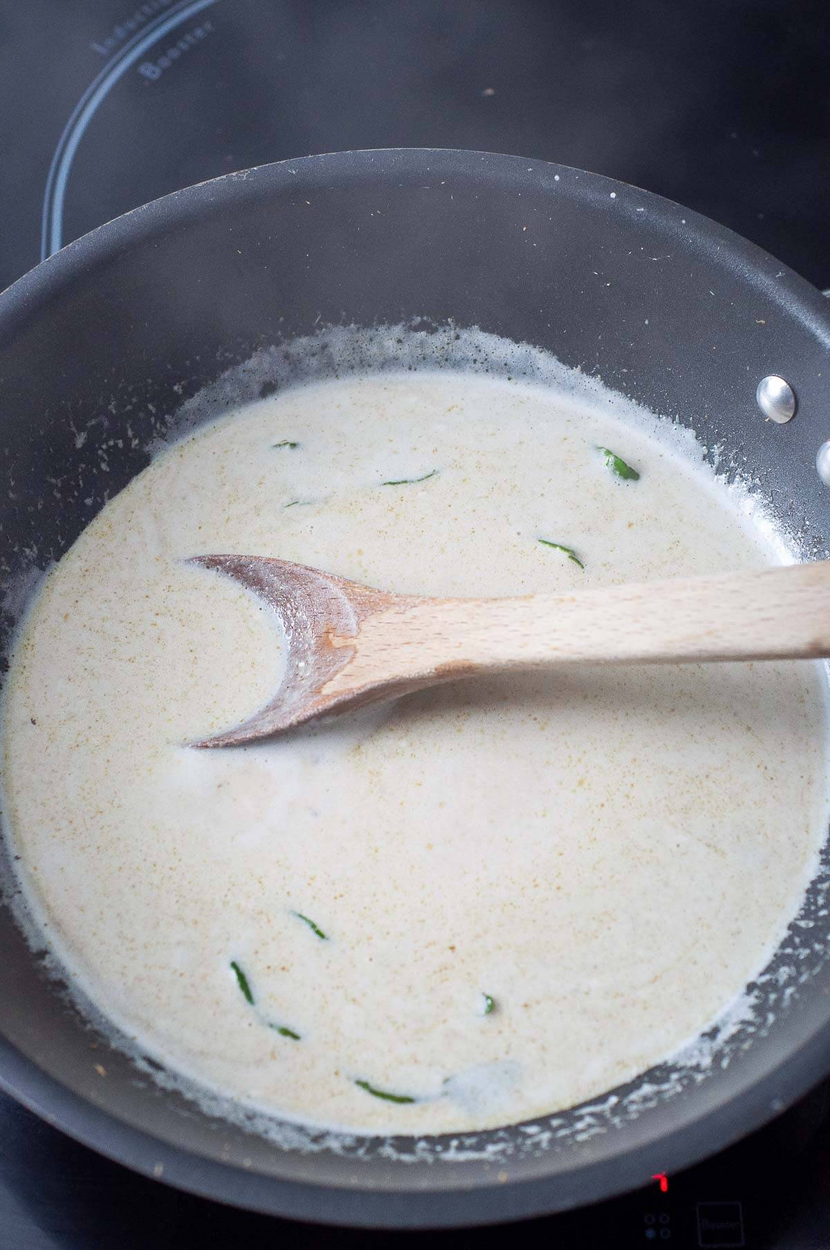 curry paste and coconut milk in a pot with stirring spoon