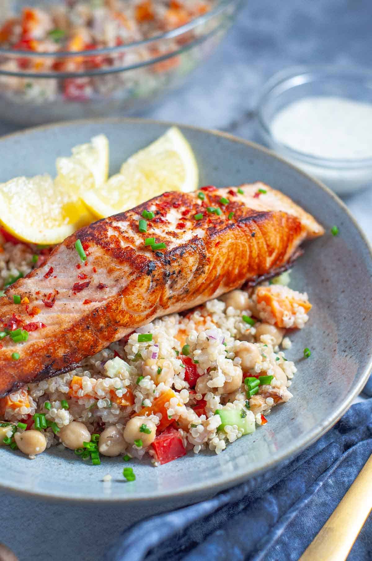 a piece of cooked salmon on top of quinoa salad