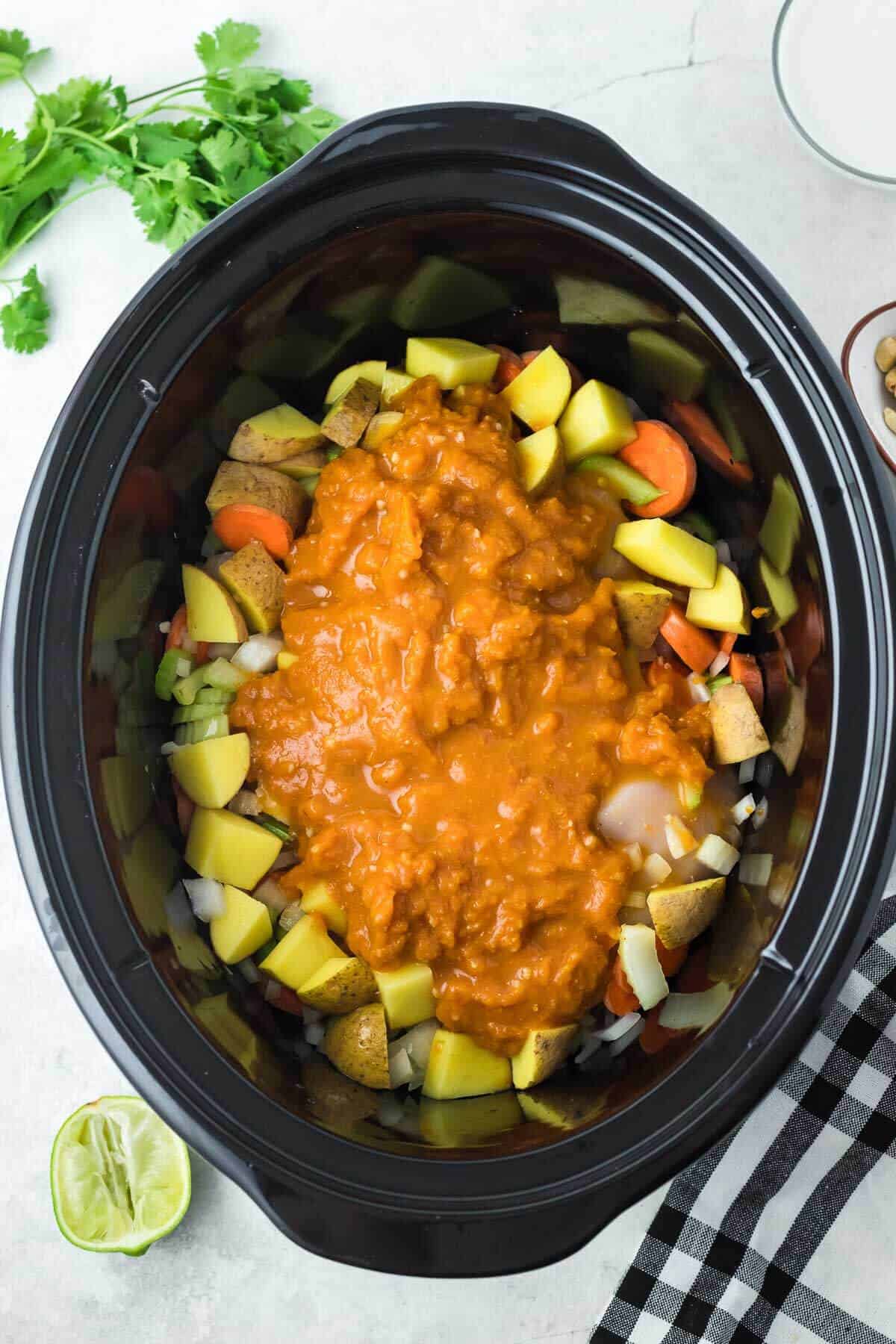 raw chicken and vegetables with curry sauce mixture in crockpot