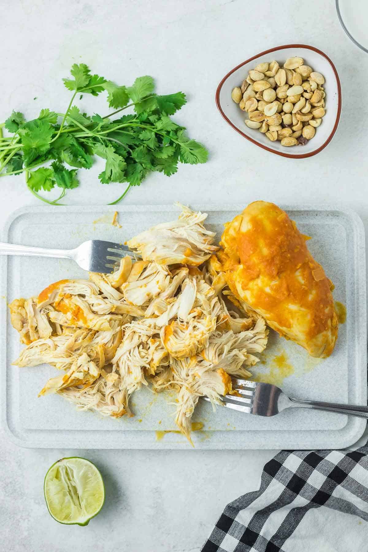 two forks shredding a chicken breast on a board