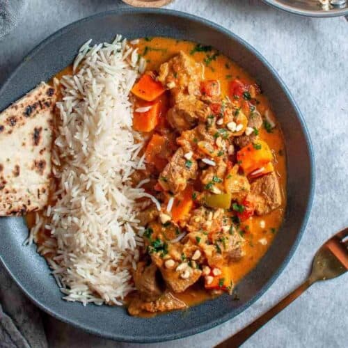 beef korma, rice and naan in a bowl