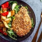 quinoa crusted chicken on a black plate with vegetables