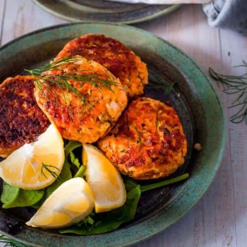 4 salmon potato fritters with lemon wedges on a plate