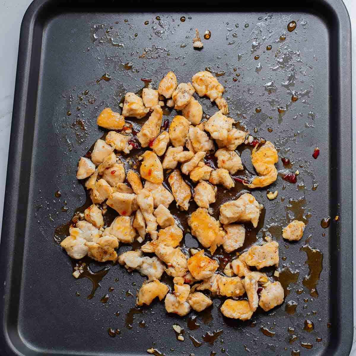 diced chicken breast on a sheet pan with chili sauce