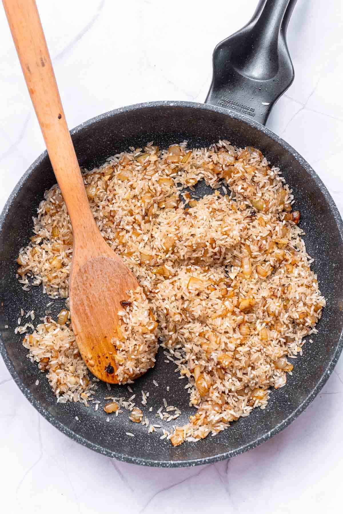 rice and onions cooking in a skillet