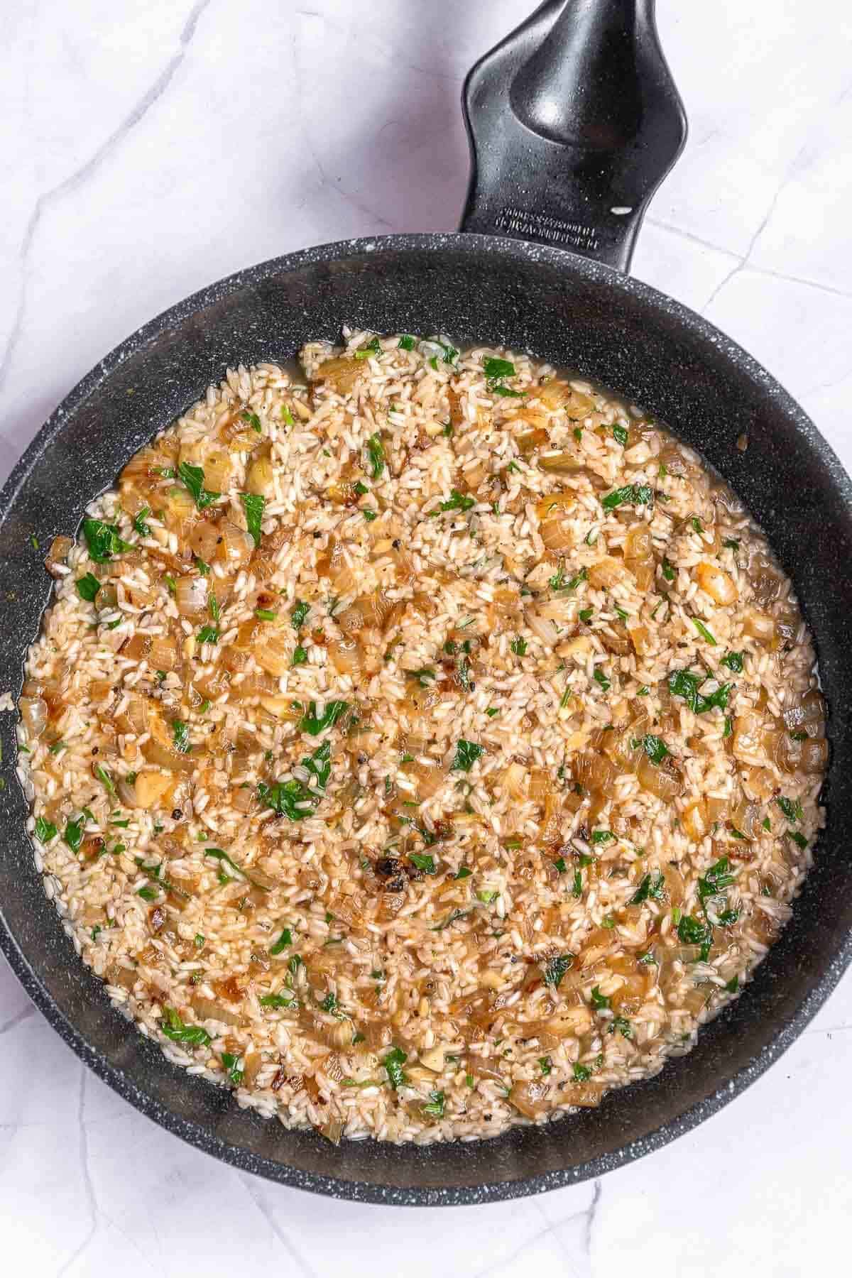 rice, onions, broth and leek cooking in a skillet
