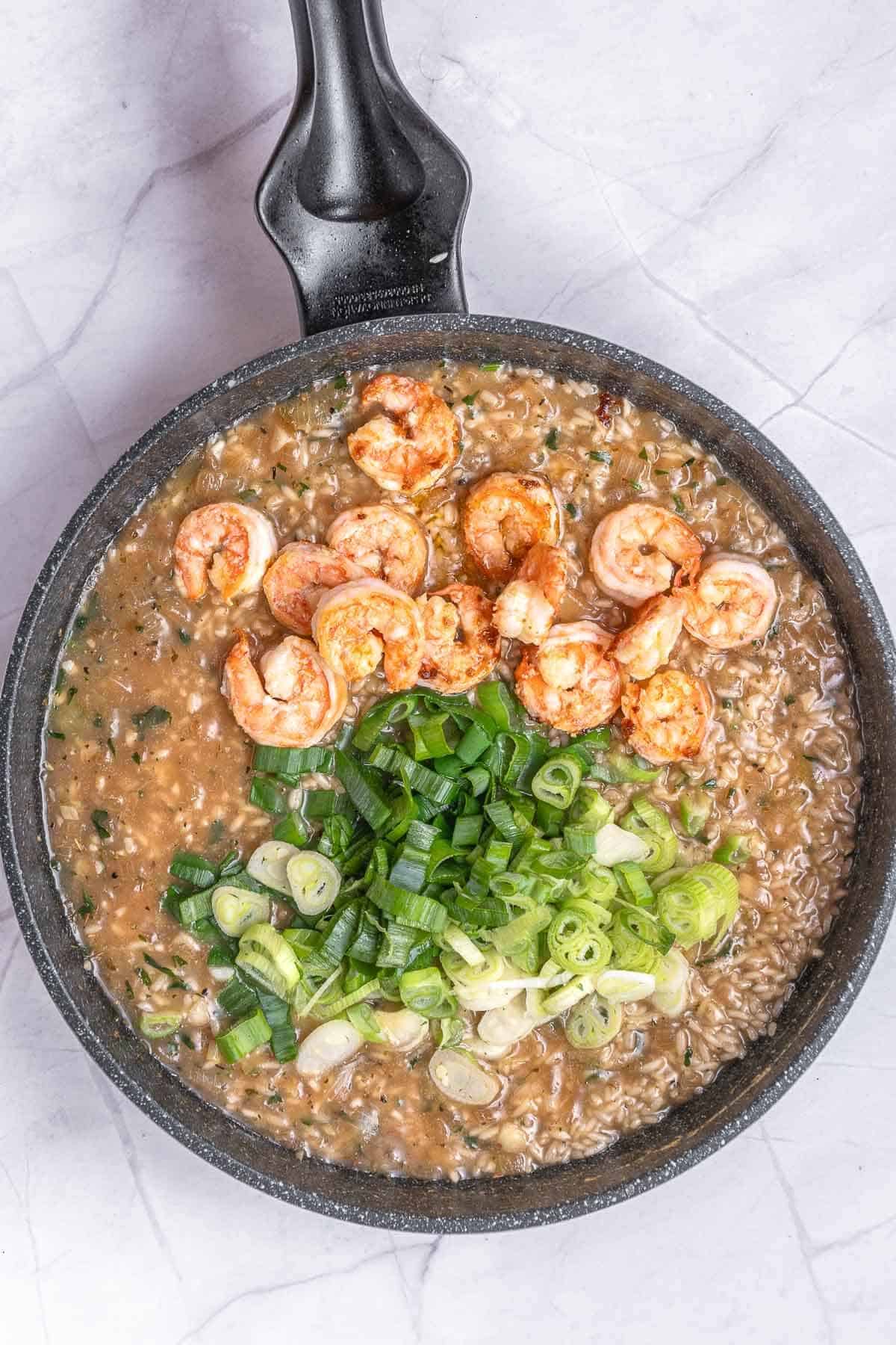 cooked shrimps, green onions in skillet with risotto rice