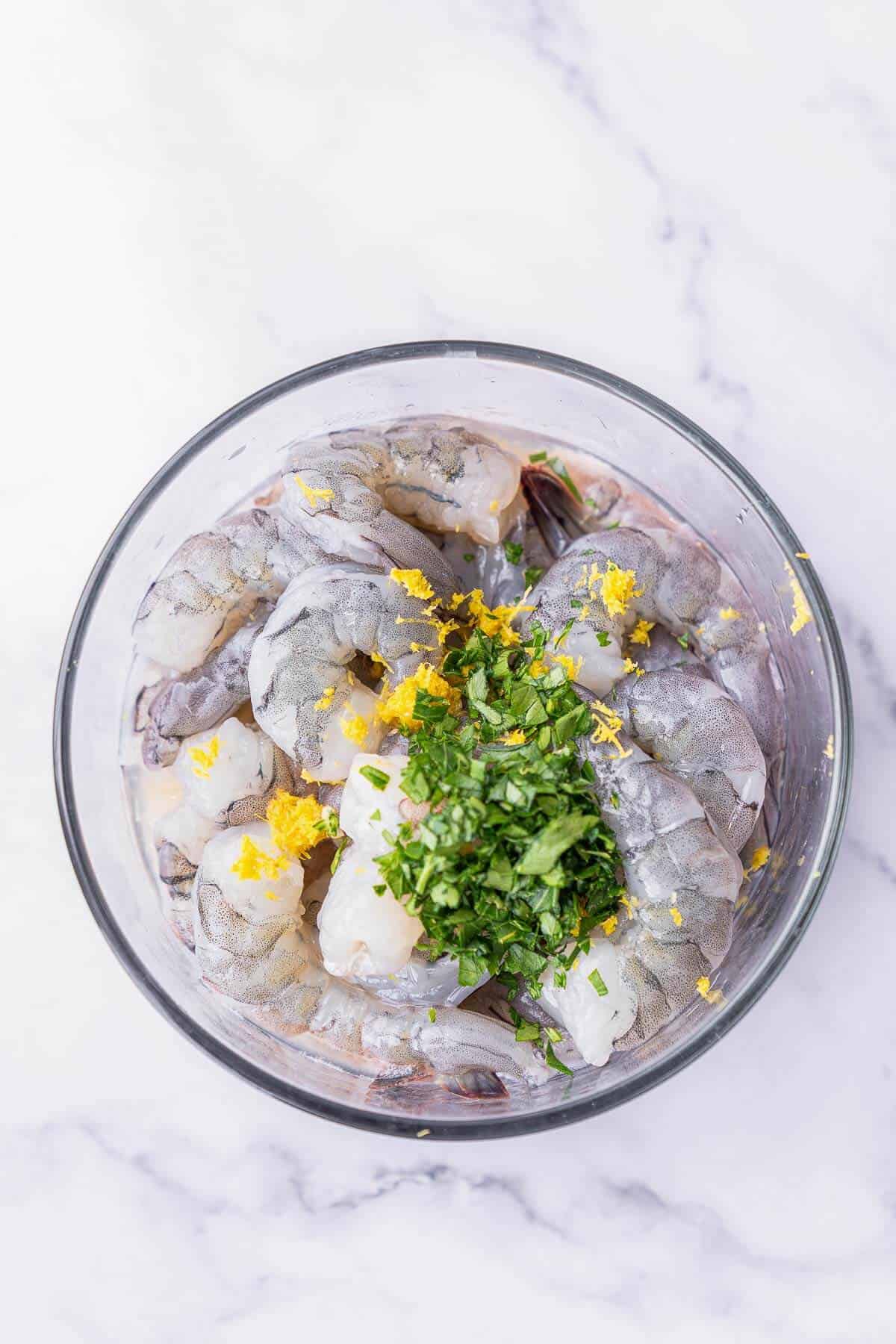 a bowl with uncooked prawns, parsley and lemon rind