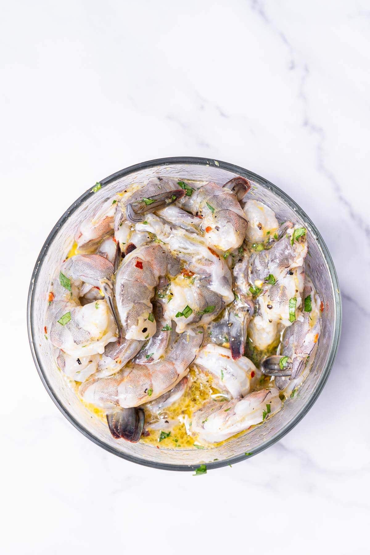 prawns in a bowl mixed with garlic, lemon, and parsley