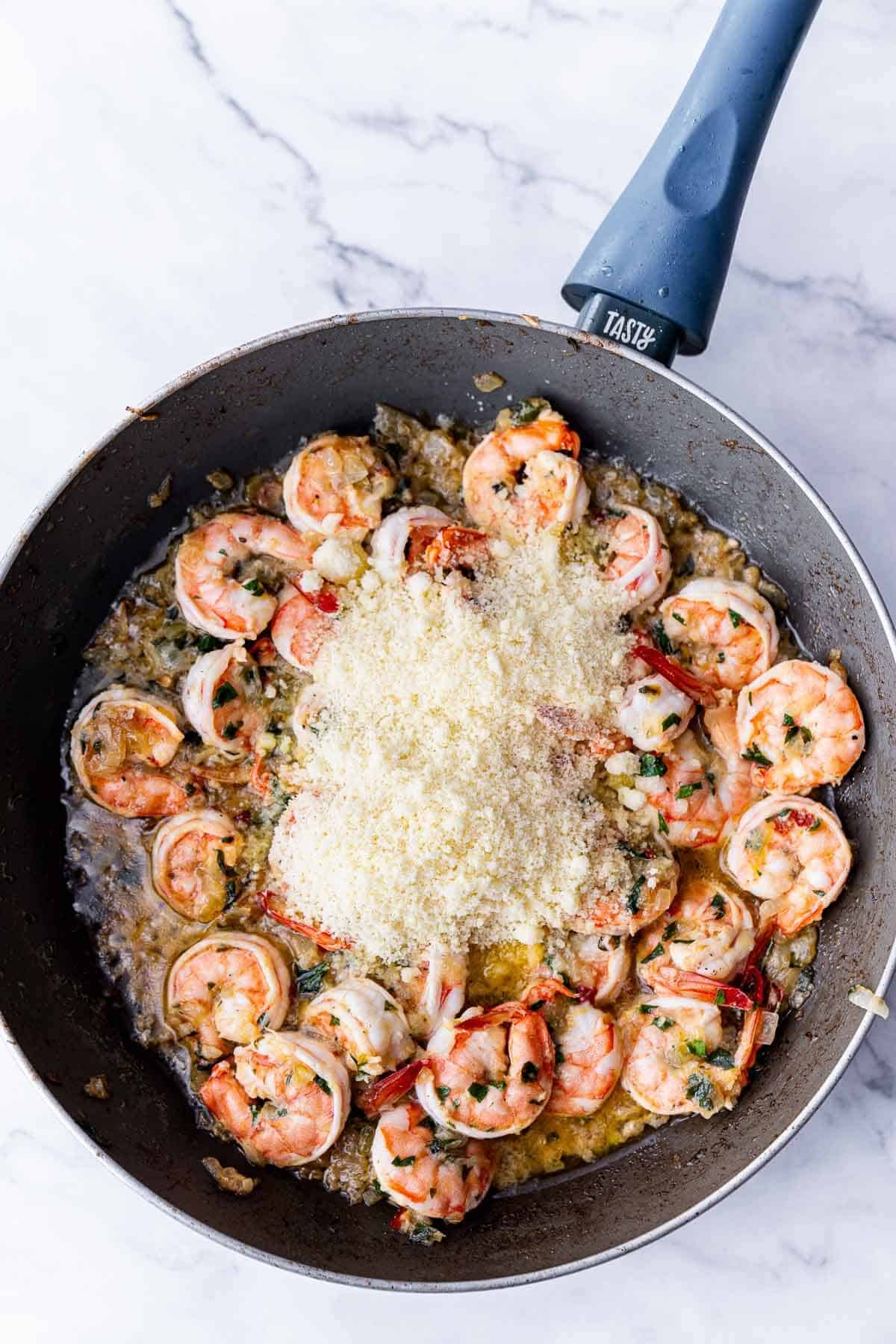 cooked prawns in a skillet with parmesan cheese on top