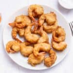 tempura shrimp cooked in a light batter scattered on a white plate