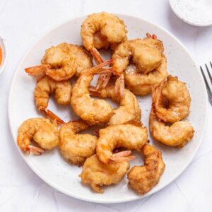 tempura shrimp cooked in a light batter scattered on a white plate