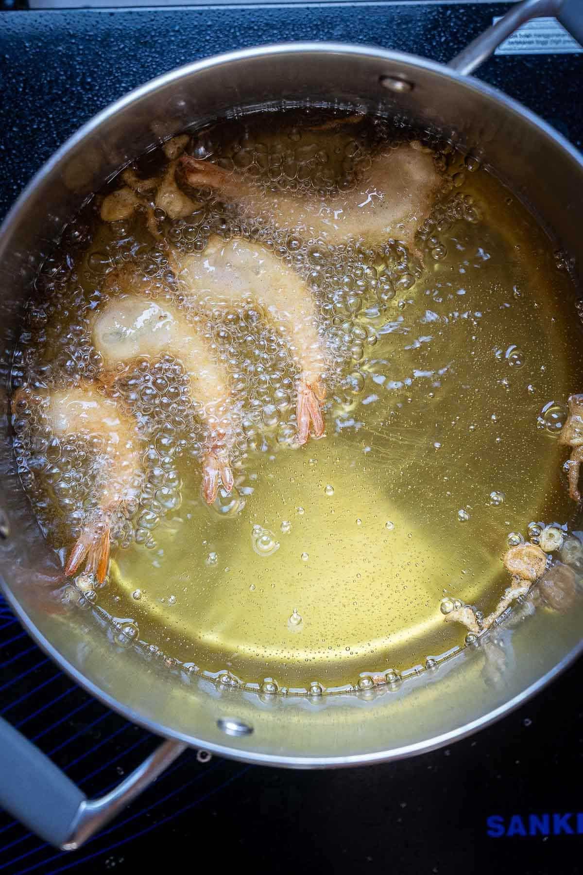 frying tempura prawns in a pot of oil