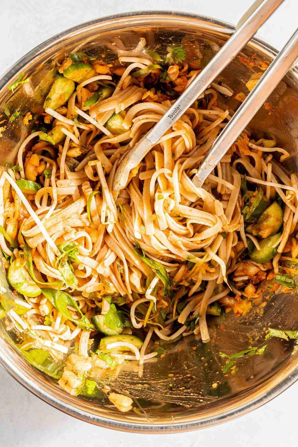 noodles and kimchi in a bowl with chopsticks