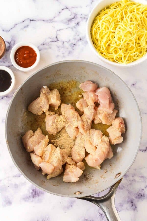 chicken breast and spices cooking in a pan