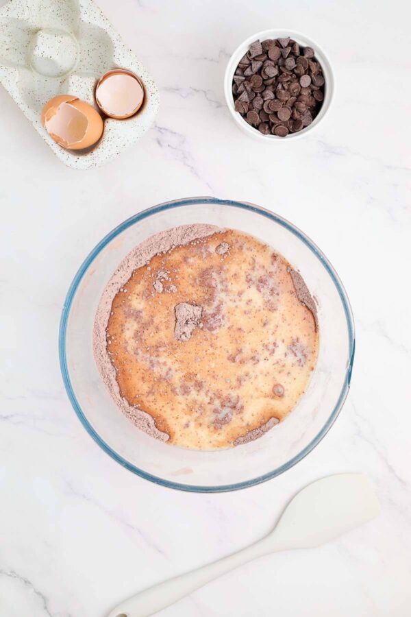 adding whisked eggs into chocolate bread dry ingredients