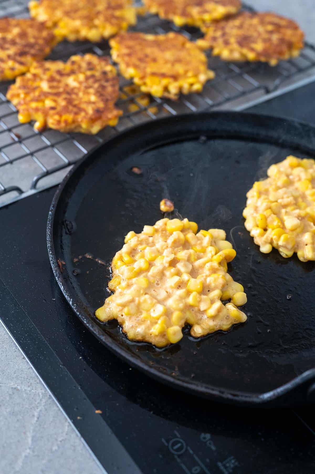 Cooking corn fritters in a skillet on the stove