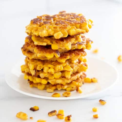 A stack of 8 low calorie corn fritters on a white plate