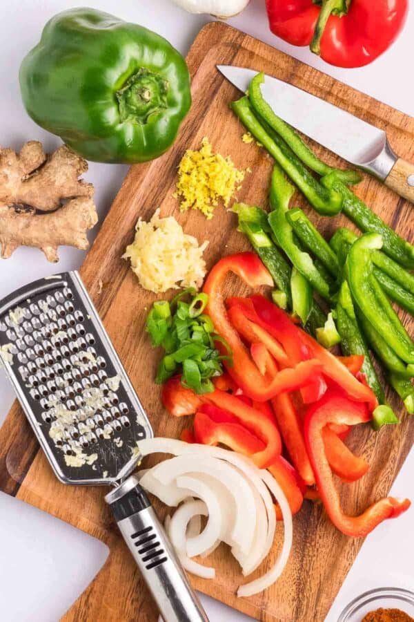 capsicums, onion, garlic and ginger on a chopping board