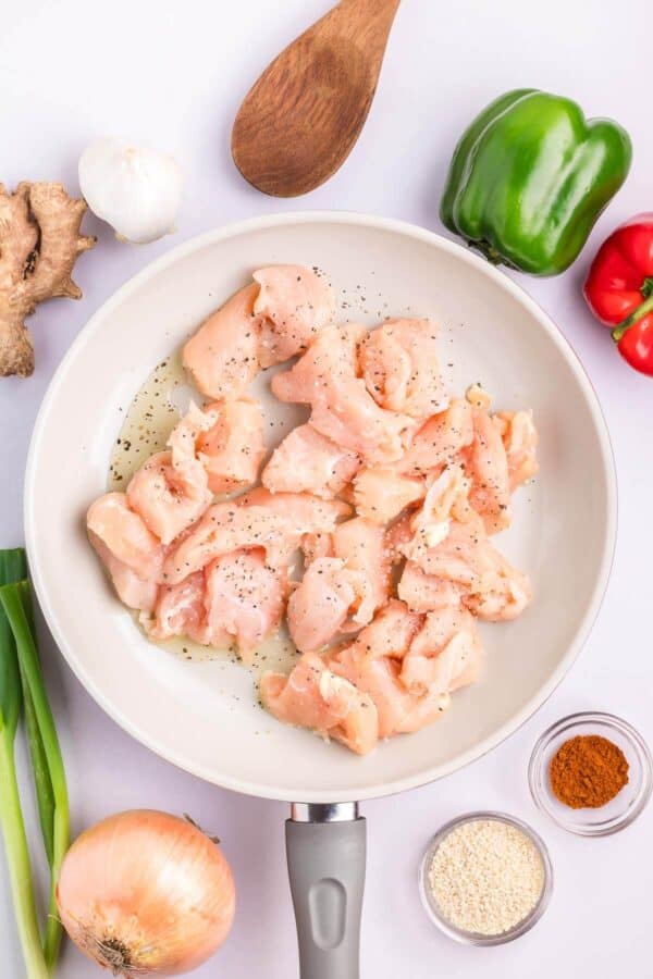 raw chicken pieces in a pan with salt and pepper