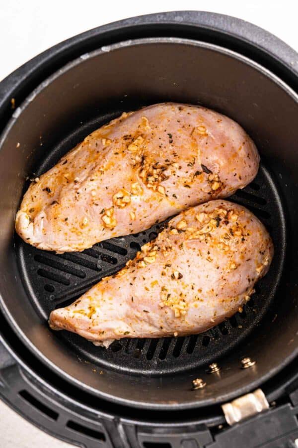 2 raw chicken breasts with garlic in an air fryer