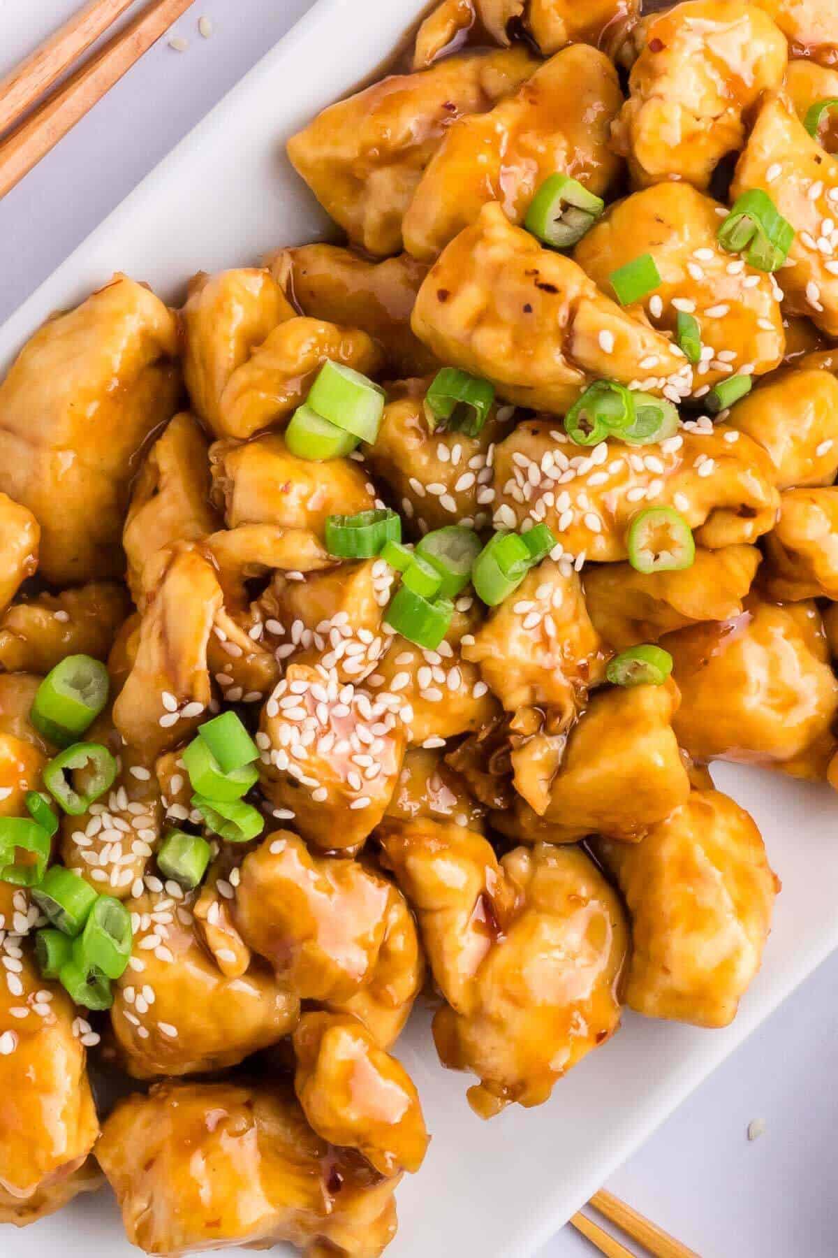 Healty General tso chicken sauce on a white plate with green onions on top