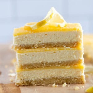 creamy lemon cheesecake bars stacked on baking paper