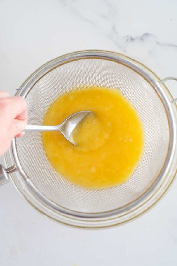 straining lemon curd through a sieve to remove lumps